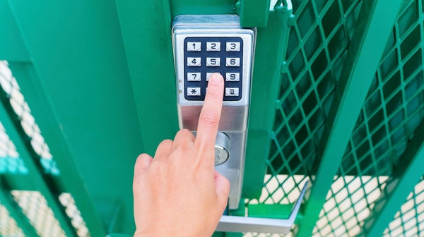 Finger pressing on the digital key lock to open a green gate